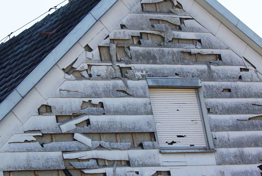 Heavily damaged siding peeled away from a building