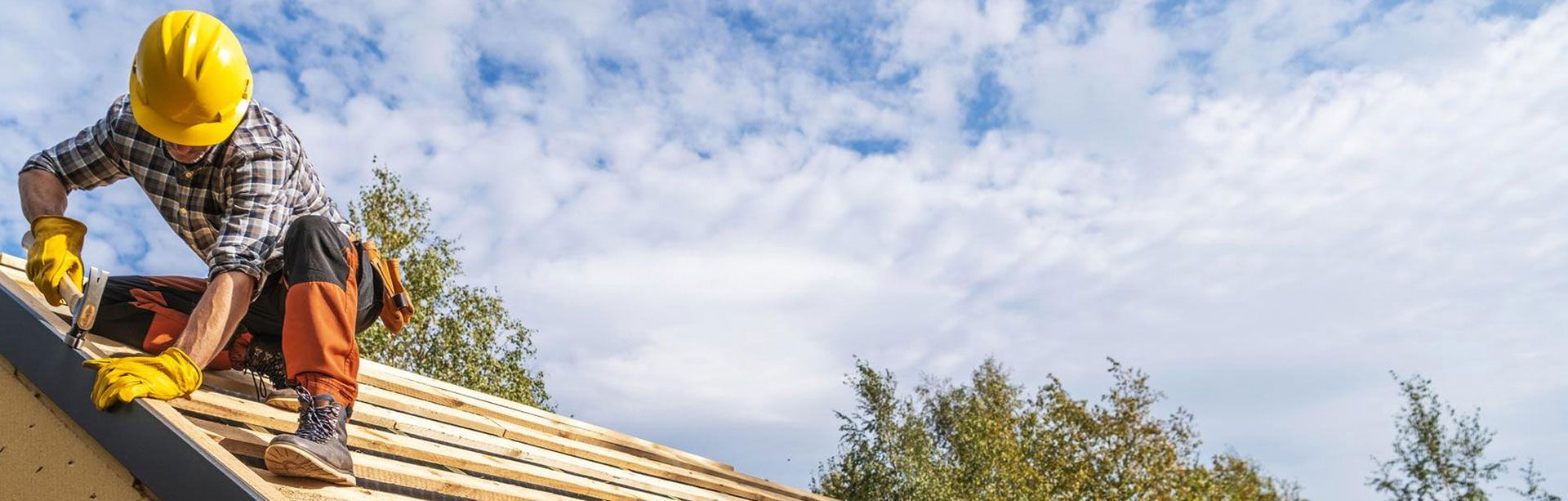 Roofer installing a new roof against a clear sky