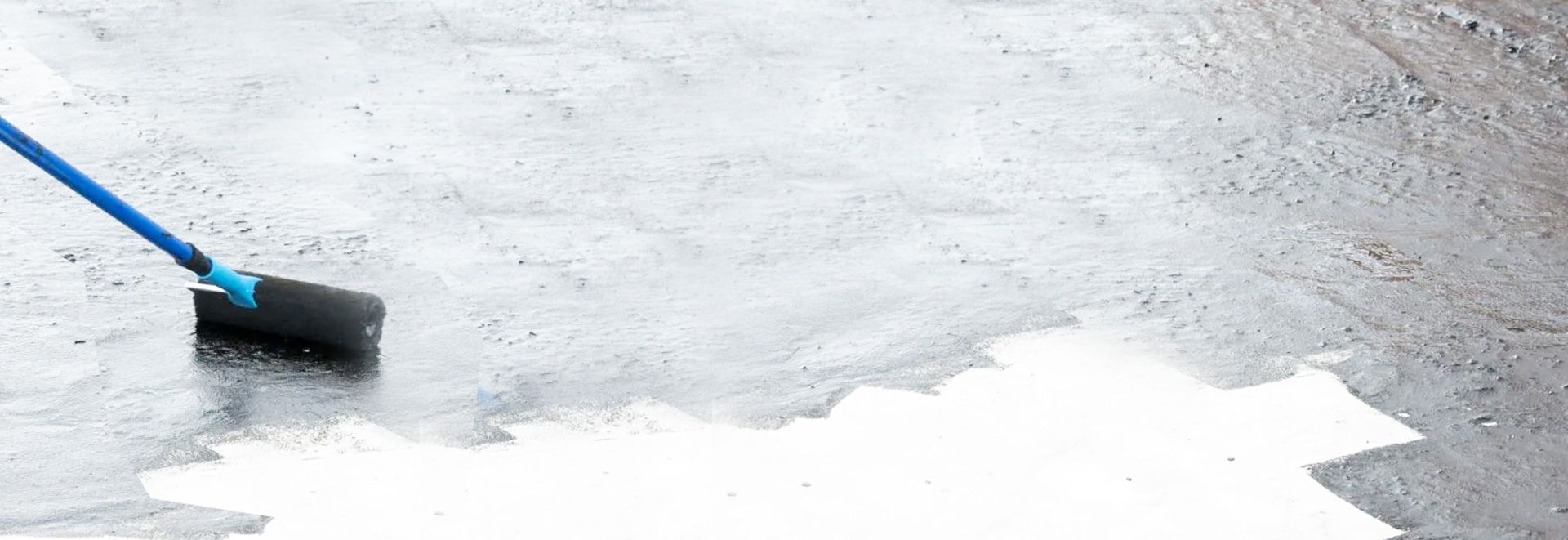 Worker rolling sealant on a flat commercial roof