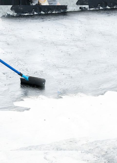 Worker rolling sealant on a flat commercial roof