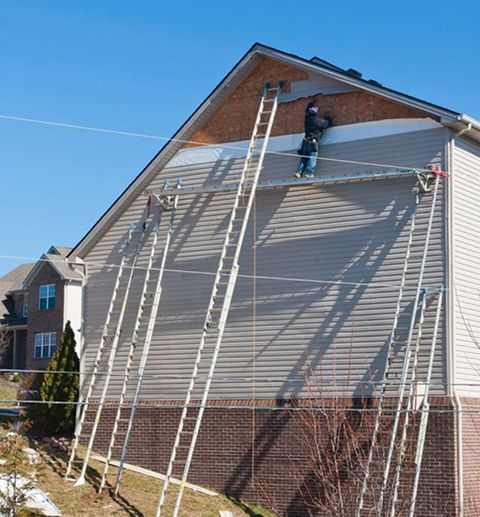 JS Exteriors crew on ladders repairing siding after a storm